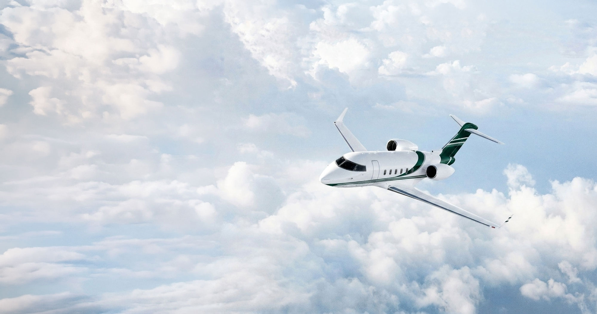 White business jet with green accents flying above bright clouds under a clear sky, showcasing premium business aviation and long-range performance.